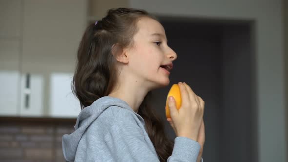 Little Girl with Long Hair is Licking a Half of the Orange