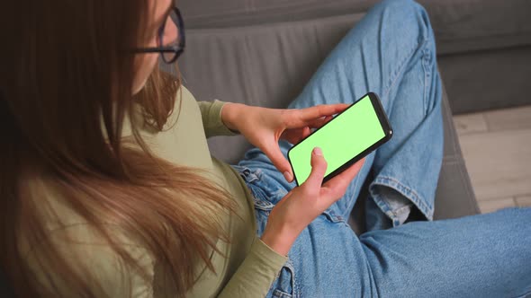 Woman sitting on a couch with Green Screen Smartphone