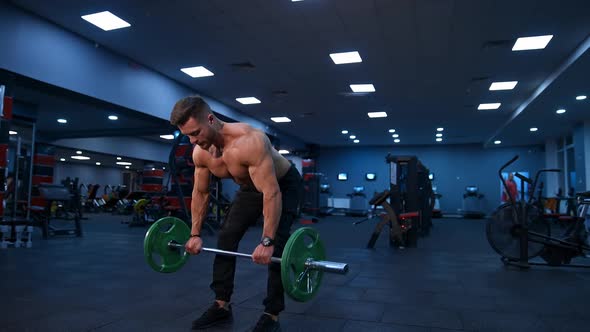 Fit young man lifting barbells doing workout at a gym.