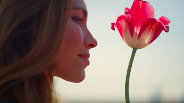 Closeup Beautiful Woman Face Enjoying Tulip Flower in Soft Sunset Light Outdoor