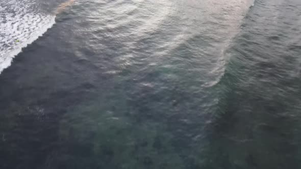 Aerial view of people surfing on waves during sunset when vacation in Bali, Indonesia.