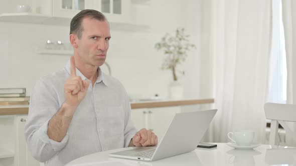 Middle Aged Man with Laptop Showing No Sign with Finger 