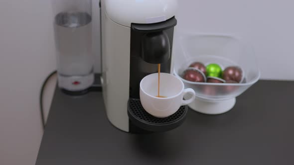 Close up view of pouring coffee from a capsule coffee machine.