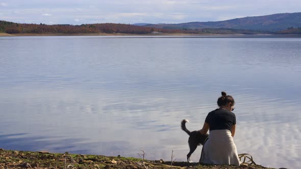 Woman and brown dog near the lake on a beautiful landscape view