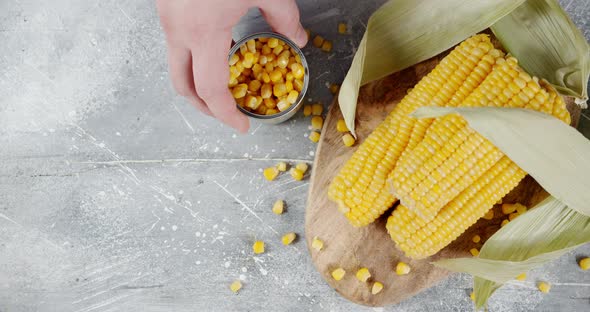 Male Hand Puts a Tin Can of Corn on the Table.