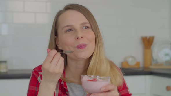 Portrait of Lovely Adult Female Tasting Delicious Yogurt with Strawberries