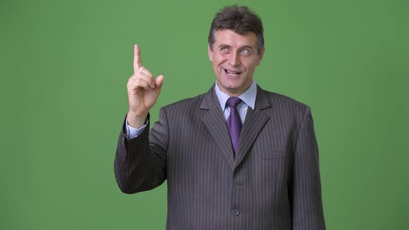 Mature Handsome Businessman Against Green Background