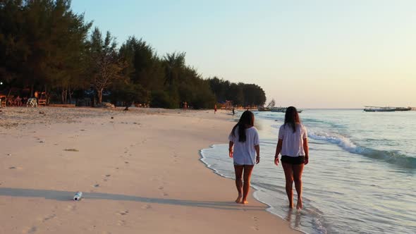 Ladies together happy together on exotic coastline beach trip by blue water with bright sandy backgr