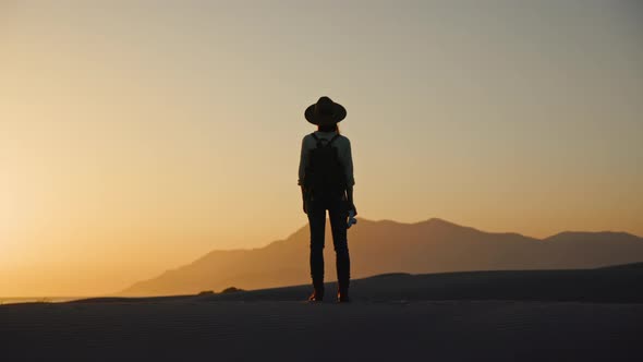 Young photographer with retro camera looking at mountains at sunset