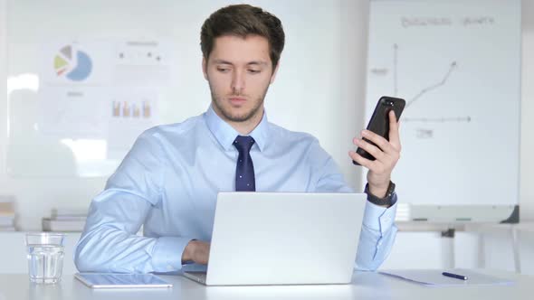 Multitasking Businessman Using Smartphone Tablet and Laptop at Work
