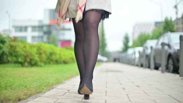 Legs of woman walking fast on the sidewalk in the street, bottom view