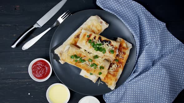 Pieces of Cheese and Spinach Wrapped Grilled Tortillas with Green Onions and Tomatoes on an Old