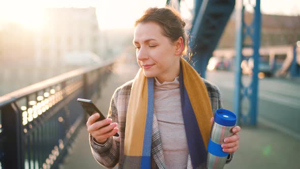 Portrait of a Young Caucasian Businesswoman in a Coat Walking Across the Bridge on a Frosty Morning