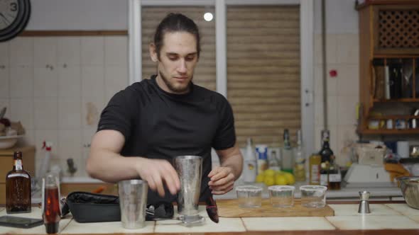 Young Male Using Cocktail Strainer to Pour Beverage in Cocktail Glasses