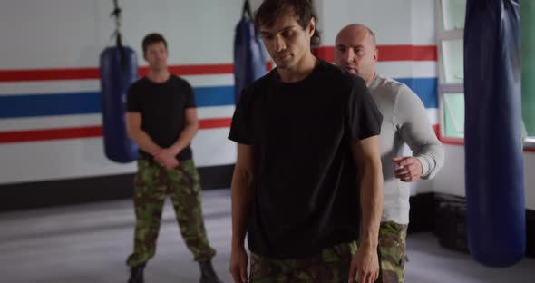 Caucasian man learning self defense from trainer in gym