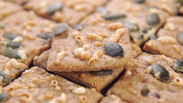 Rye crispbreads with pumpkin seeds, stacked in rows, rotate. Falling cracker in slow motion
