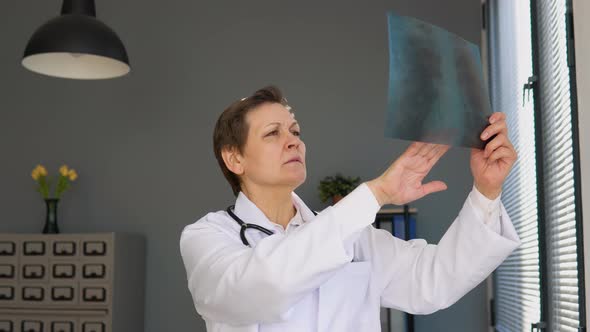 Senior Female Doctor in Her 50s Examining an Xray of the Lungs of a Covid 19 Patient