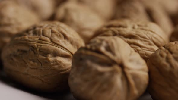 Cinematic, rotating shot of walnuts in their shells on a white surface - WALNUTS 