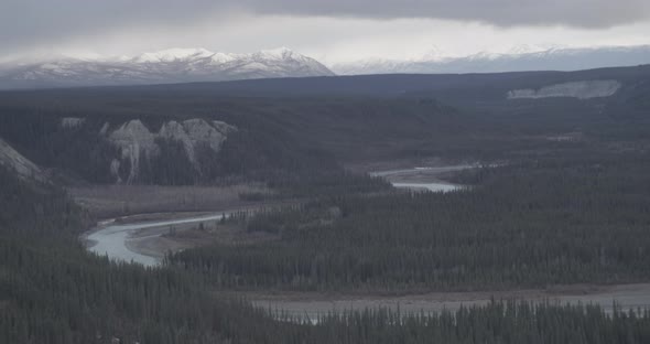 Aerial helicopter shot flying past houses on a hill, mountains in the distance, misty clouds, drone 