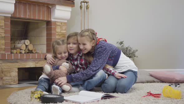 Camera Approaching To Cute Caucasian Teenager Hugging Little Boy and Girl. Siblings Looking at