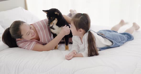 Mother and daughter playing with black dog on bed (5)