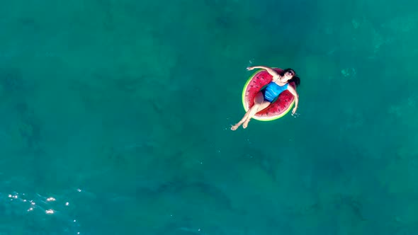A Woman Is Floating Along the Sea in a Rubber Ring in a Top View