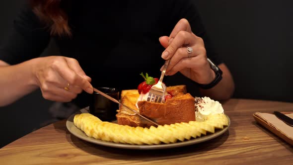 Hands holding forks and knifes cutting on Honey toast