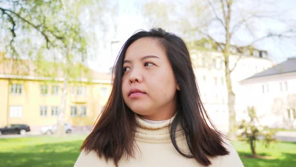 Front view of Asian black straight hair woman walking and looking around a park