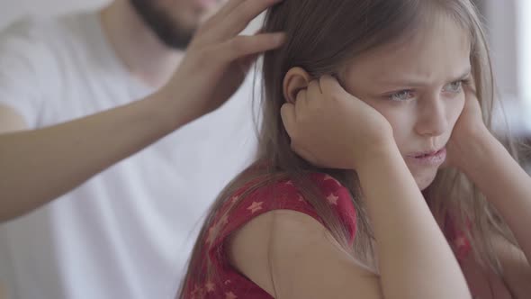 Close Up Portrait of Sad Little Girl Sitting on the Foreground Holding Her Head in Hands