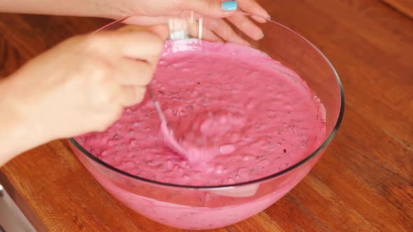 Woman Prepares Cold Beetroot Soup in Glass Bowl on Wooden Table