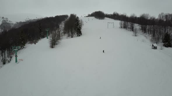 Carpathian Ski Resort From a Height. Flight Over Mountains. Bird's Eye View of People Descending on