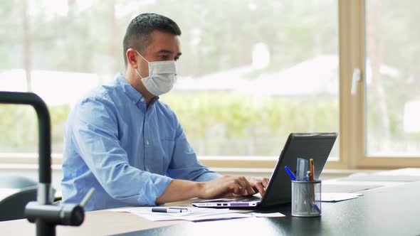 Man in Mask with Laptop Working at Home Office