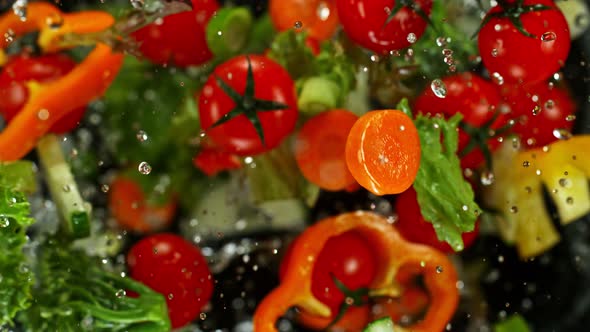 Super Slow Motion Shot of Flying Cuts of Colorful Vegetables and Water Drops on Black at 1000Fps.