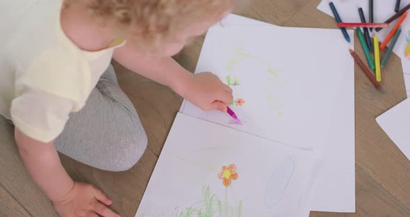 Close Up of a Hands and Head of a Little Girl Who is Drawing with Pencils on the White Paper on the