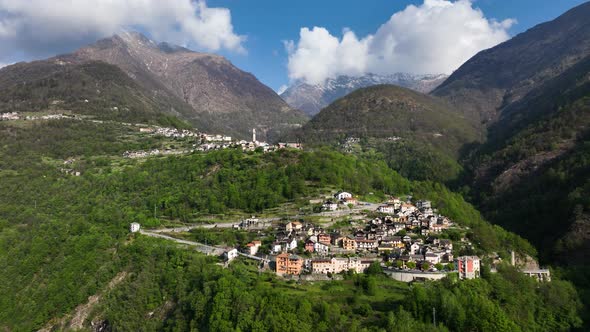 Drone crane motion toward picturesque Alp village in lush hillside forest