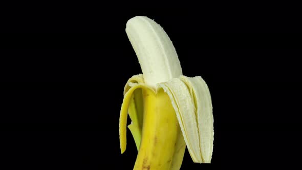 Animated Footage of a Half Peeled Banana Turning Against Black Background