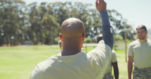 Stern african american male soldier instructing diverse group at obstacle course, turning to camera