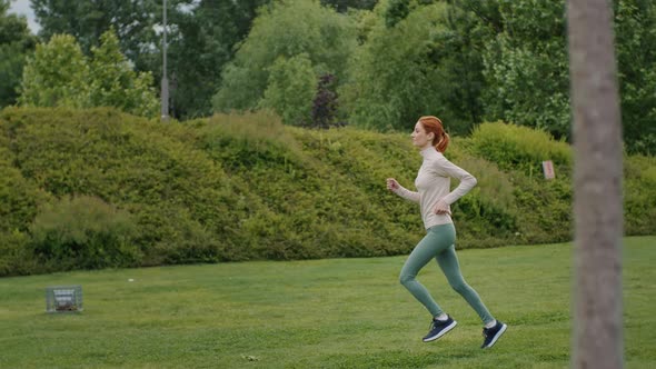 Woman runs in park at dawn in summer.