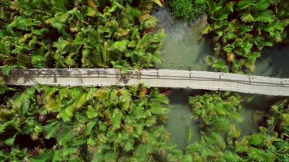 Aerial view of woman walking on long wooden bridge in Bojo river, Philippines.