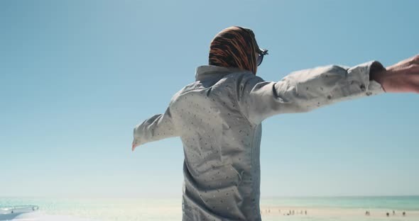 Man Stands in Strong Wind and Opens His Arms to Sides Closeup