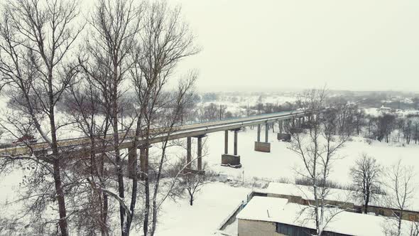 Snowy Winter Landscape with Frozen River and Road Bridge Aerial View