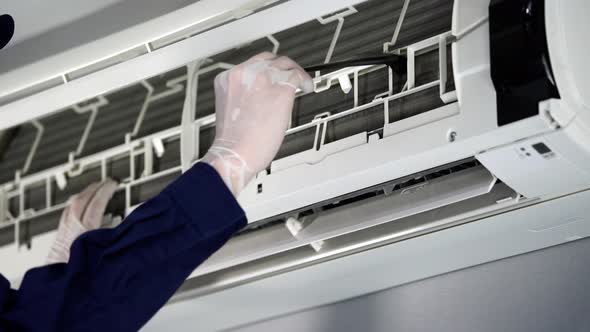 close up technician service using brush to cleaning the air conditioner indoors