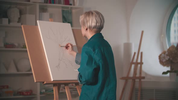 A Young Woman Artist Starts Painting Her Sketch in Beige Color in the Art Studio