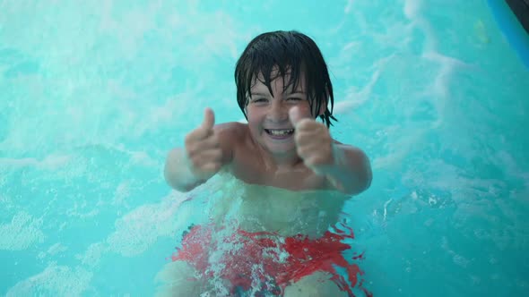 Joyful Boy Showing Thumbs Up Smiling Looking at Camera Standing in Bubbling Azure Blue Water in