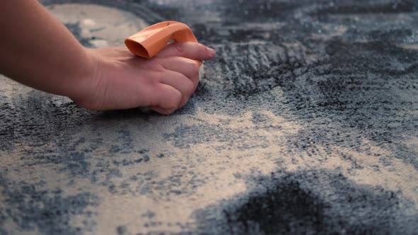 Hand wash the carpet. A woman with an orange brush and foam cleans the surface of the carpet