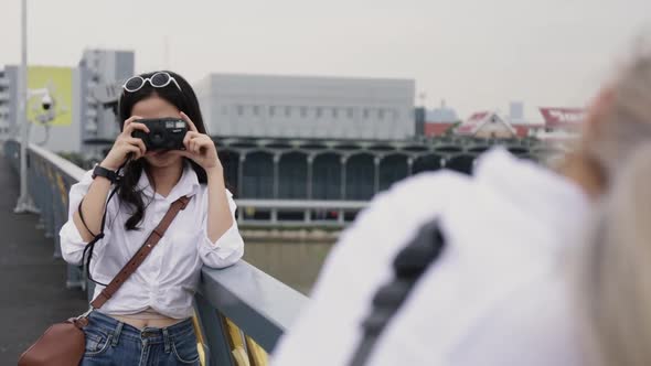 Asian lesbian couples enjoying traveling using film camera taking a photo.