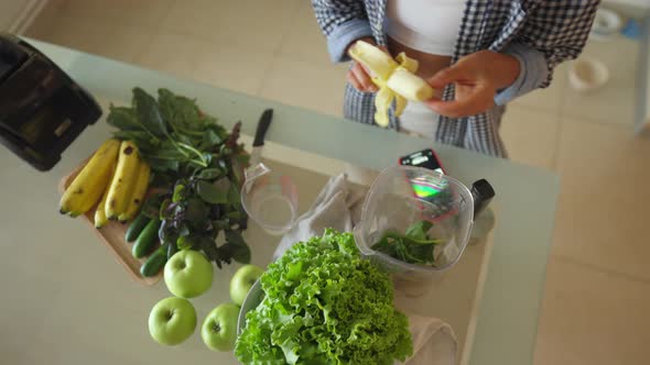 Young Sportswoman Putting Washed Greenery on Table and Cooking Smoothie