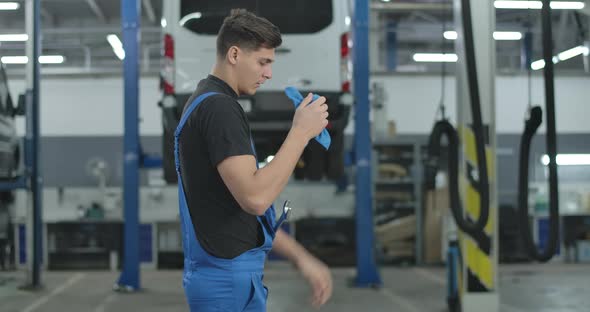 Serious Tired Auto Mechanic Cleaning Hands Throwing Cloth on Floor and Walking Away