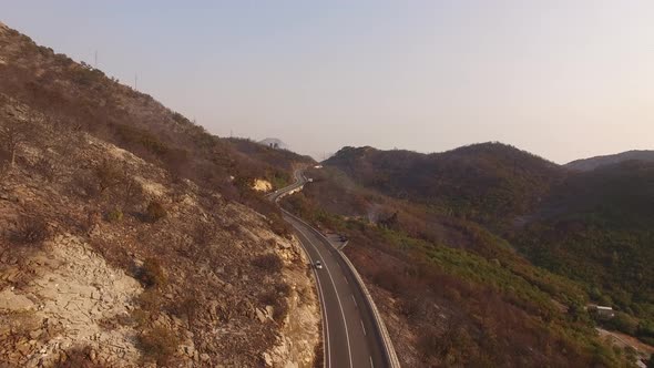 Drone View of the Highway with Passing Cars and a Burnt Forest in the Mountains