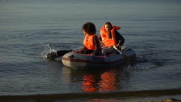 Two Women in Life Jackets Rowing Boat, Flood Survivors Seeking Help Ashore